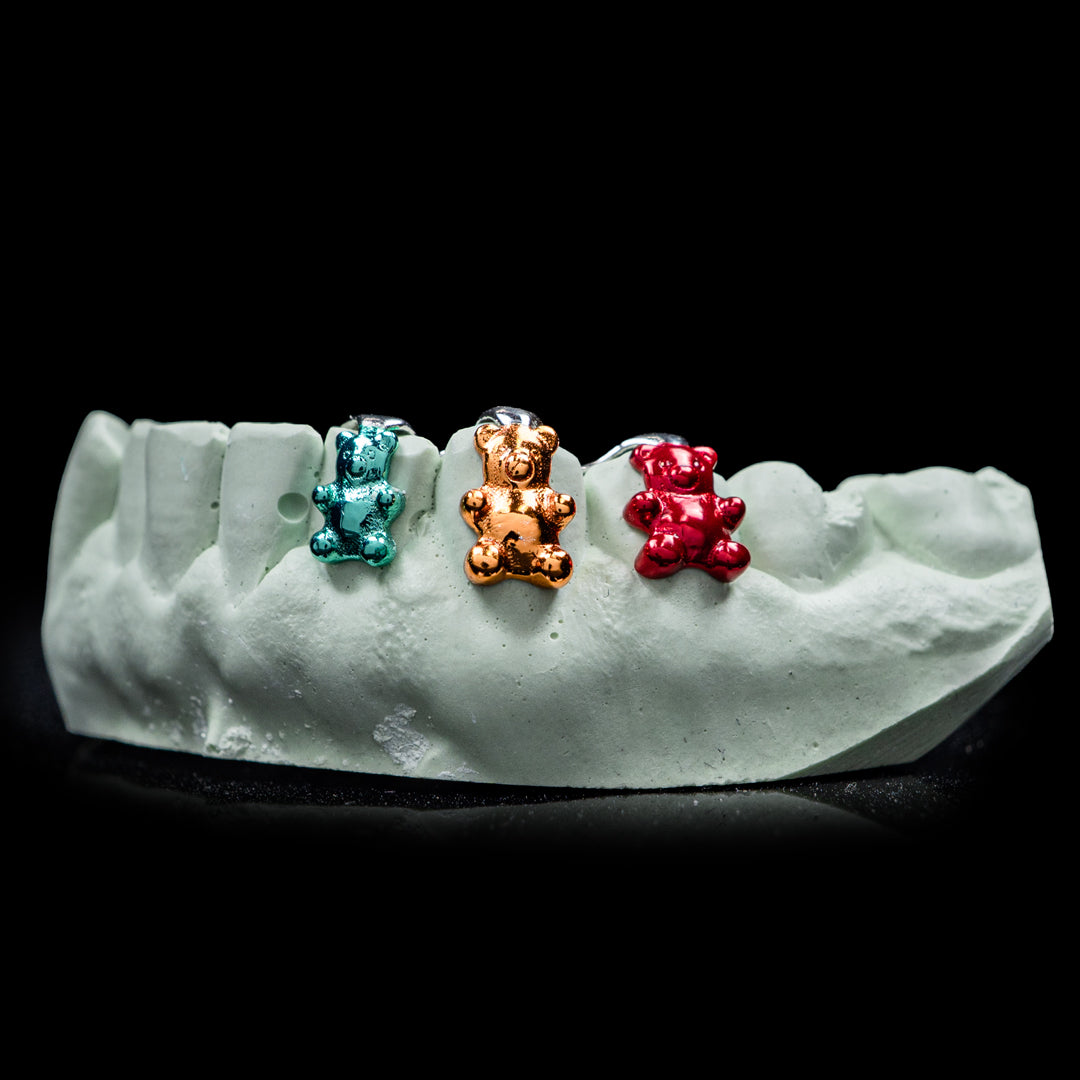 Three sculpted Gummy Bear grill caps with colorful enamel