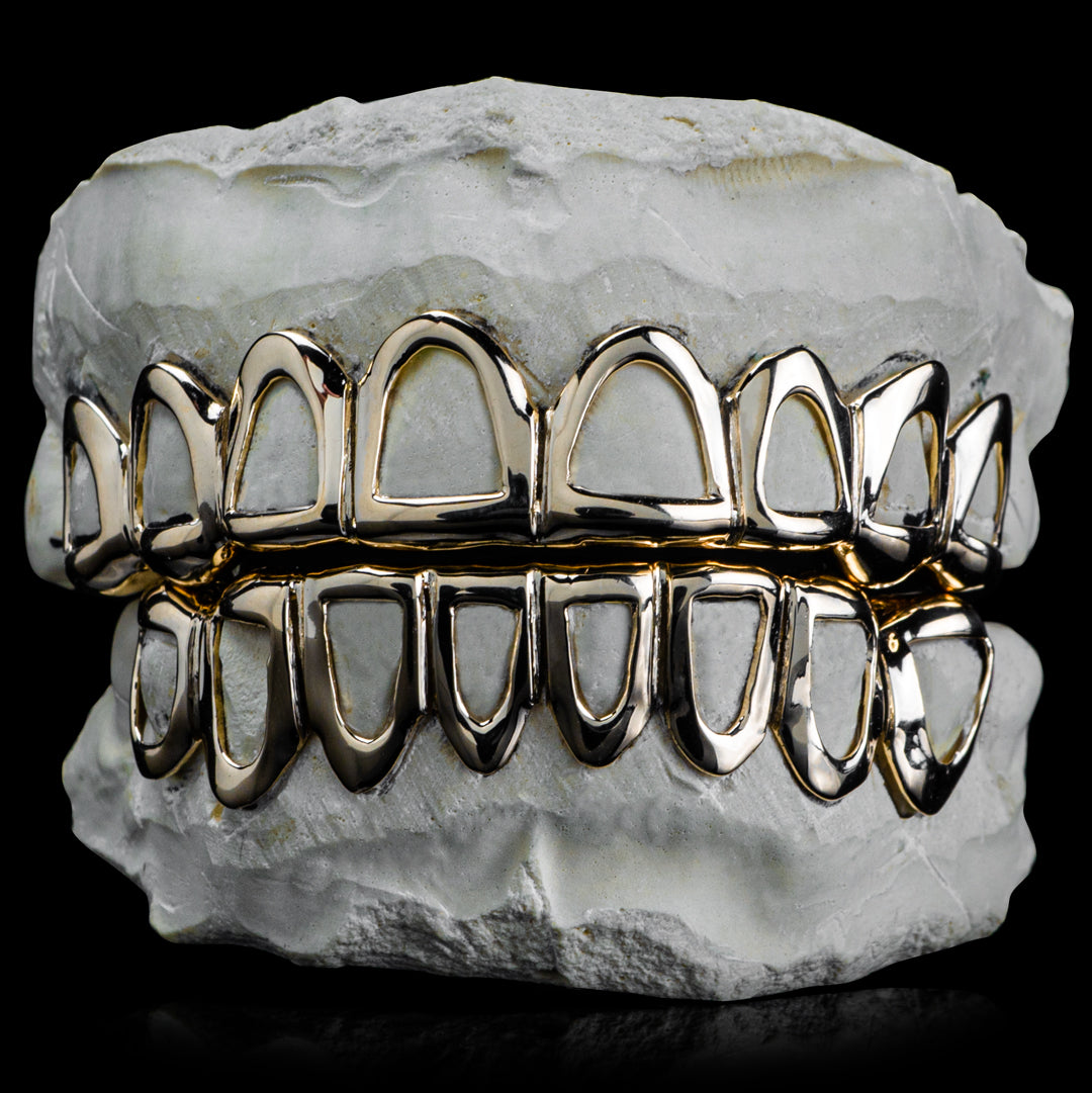 Top and bottom open-face grillz with polished borders around each tooth, displayed on a dental model.