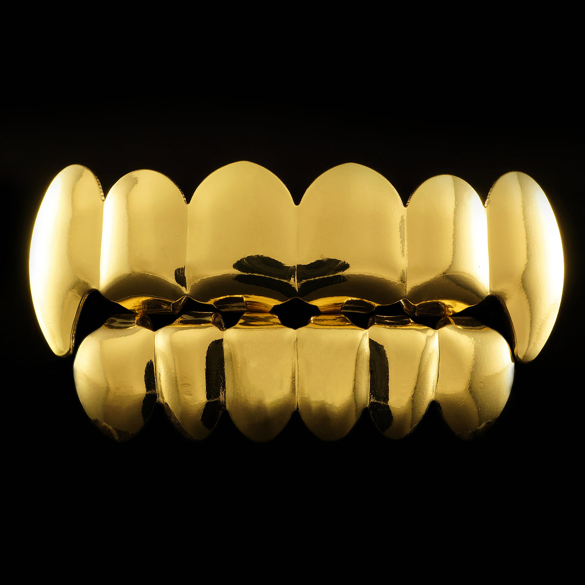 Gold-tone top and bottom grillz with long fang tips on the upper row, shown against a black background.