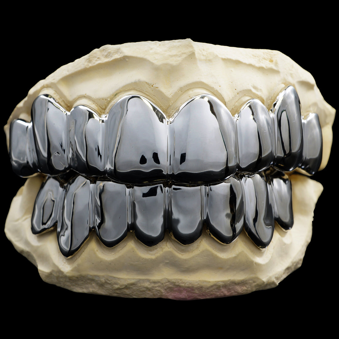 Silver-tone top and bottom grillz with smooth, polished tooth caps, displayed on a dental model.